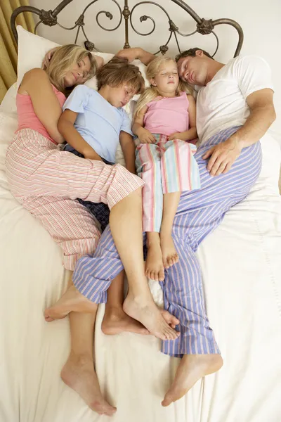 Familia relajándose en la cama en casa — Foto de Stock