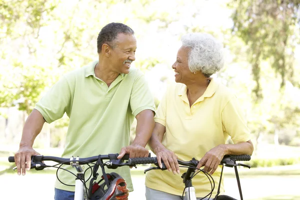 Senior Couple Riding Bikes In Park Stock Photo