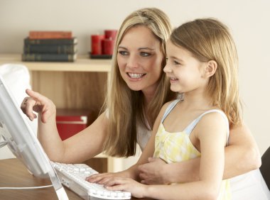 Mother And Daughter At Home Using Computer clipart