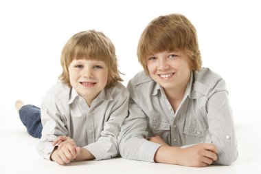 Two Young Boys Lying On Stomach In Studio clipart