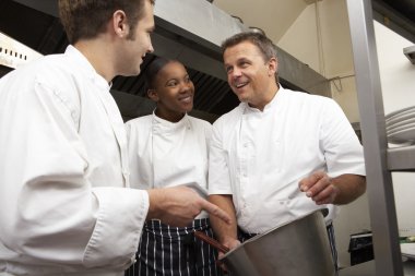 Chef Instructing Trainees In Restaurant Kitchen clipart