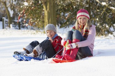 Mother Riding On SledgesThrough Snowy Landscape clipart