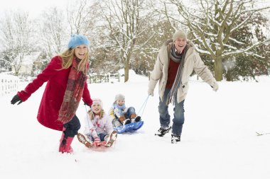 Family Pulling Sledge Through Snowy Landscape clipart