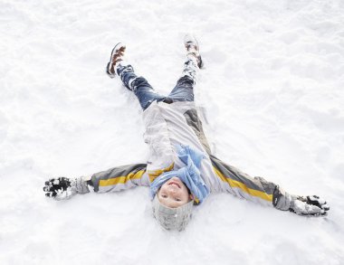 Boy Laying On Ground Making Snow Angel clipart