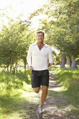 Middle Aged Man Jogging In Park clipart