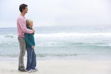 Father And Son Standing On Winter Beach Together clipart