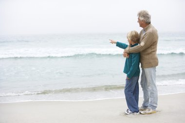 Grandfather And Son Standing On Winter Beach Together clipart