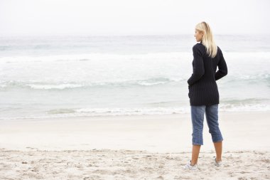 Young Woman On Holiday Standing On Winter Beach clipart