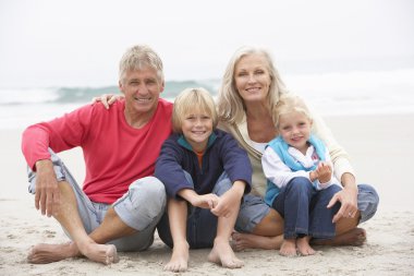 Grandparents And Grandchildren Sitting On Winter Beach Together clipart