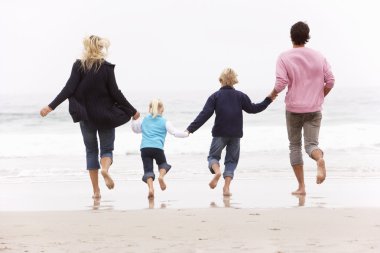 Back View Of Young Family Running Along Winter Beach clipart