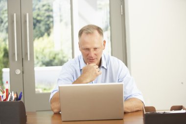 Middle Aged Man Using Laptop At Home clipart