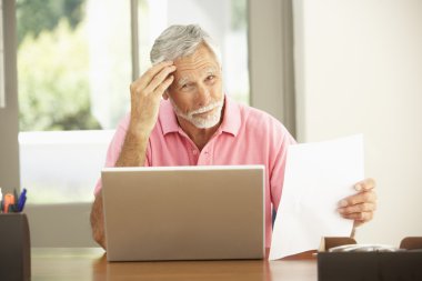 Senior Man Using Laptop At Home clipart
