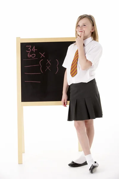 Nachdenkliche Studentin in Uniform neben Tafel — Stockfoto