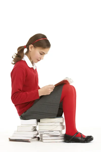 stock image Female Student In Uniform Sitting On Pile Of Books Reading