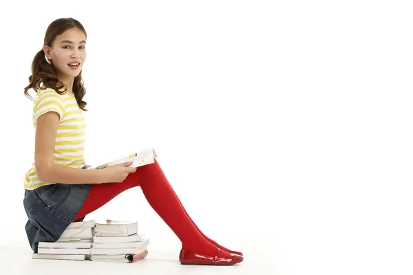 読書本の山に座っている若い女の子 — ストック写真