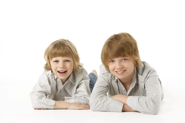Two Young Boys Lying On Stomach In Studio — Stock Photo, Image