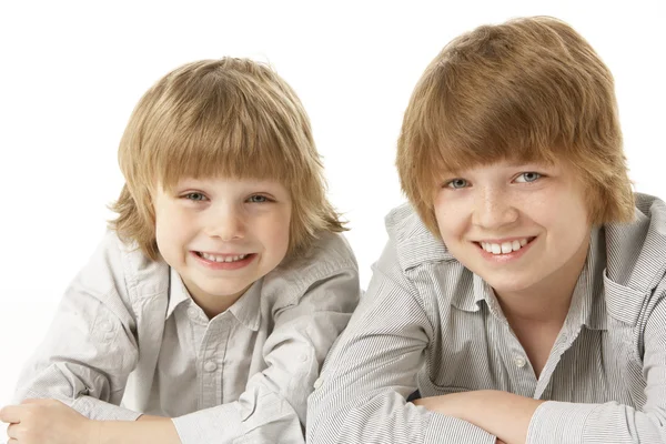 Twee jonge jongens liggend op de buik in studio — Stockfoto