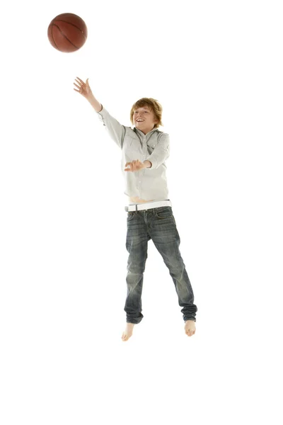 Ung pojke hoppar med basket i studio — Stockfoto