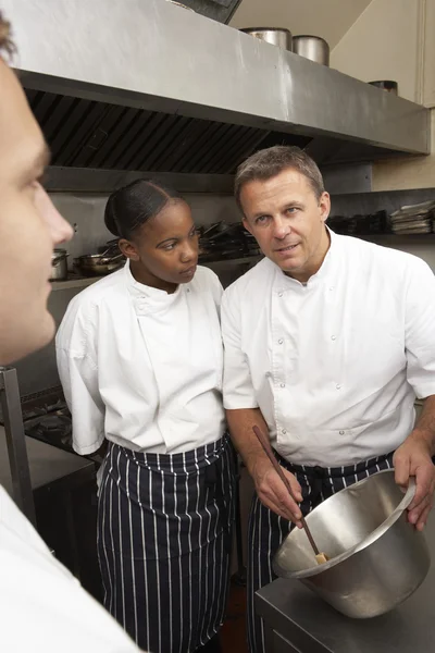 Chef-kok instrueren stagiairs in restaurant keuken — Stockfoto