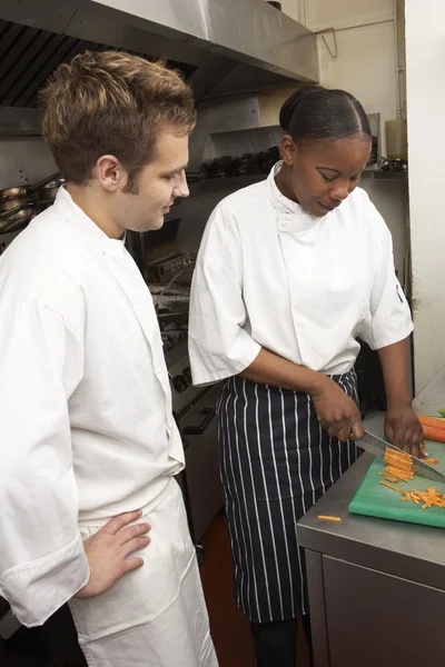 Шеф-повар инструктирует стажера на кухне ресторана — стоковое фото