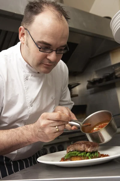 Chef Adicionando molho ao prato na cozinha do restaurante — Fotografia de Stock