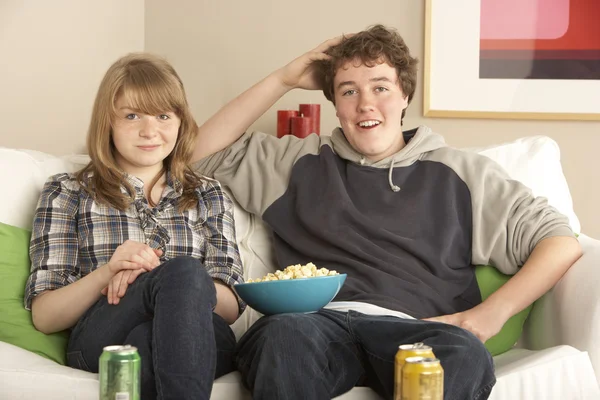 テレビを見ながらソファに座っている十代のカップル — ストック写真