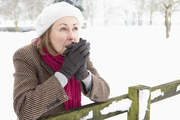 Seniorin steht draußen in verschneiter Landschaft und wärmt Hände — Stockfoto