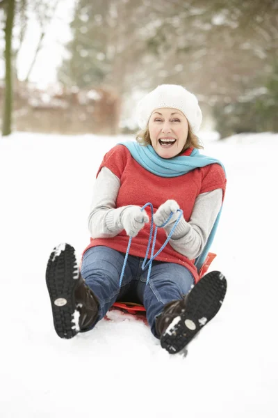 Senior mulher Sledging através de neve Woodland — Fotografia de Stock