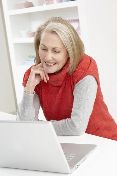 Evde dizüstü bilgisayar kullanan yaşlı bir kadın. — Stok fotoğraf