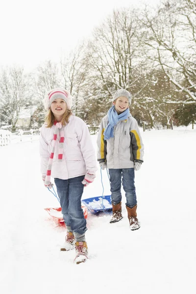 子供たちは雪の風景を介してそりを引っ張る — ストック写真
