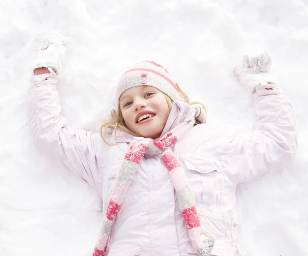 Chica acostada en tierra haciendo ángel de nieve — Foto de Stock