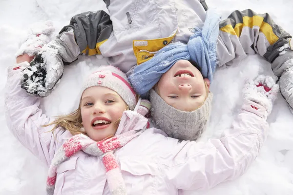Дети Лежащие Земле Делают Снежного Ангела — стоковое фото