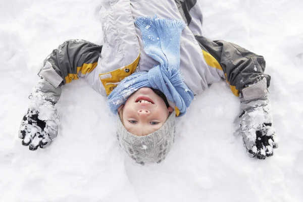 Хлопчик лежить на землі роблячи сніговий ангел — стокове фото