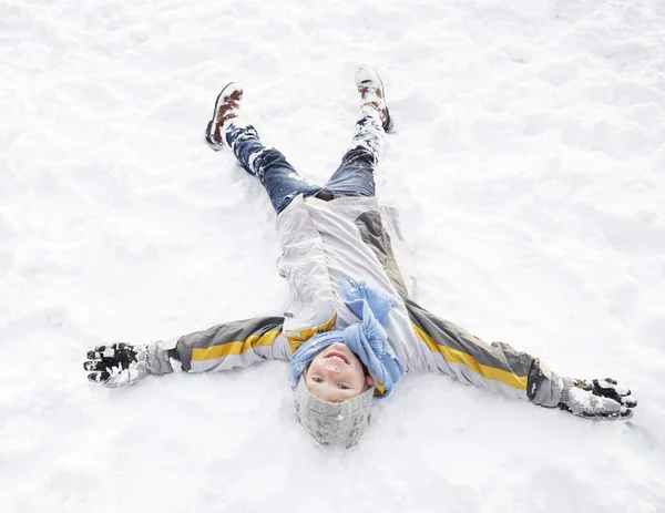 少年の雪の天使を作る地面に敷設 — ストック写真