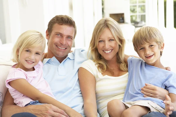Familie sitzt lächelnd im Wohnzimmer — Stockfoto