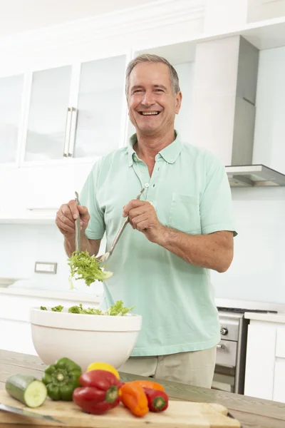 Homem sênior preparando salada em — Fotografia de Stock