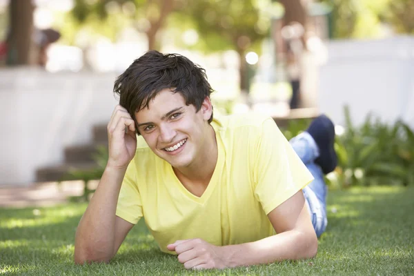 Портрет мальчика-подростка, лежащего в парке — стоковое фото
