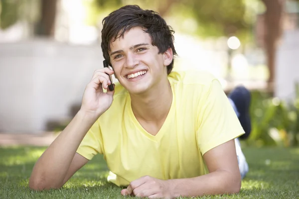 Tonårspojke i parken med hjälp av mobiltelefon — Stockfoto