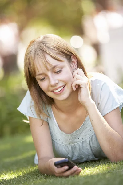 Tonårig flicka i parken med hjälp av mobiltelefon — Stockfoto