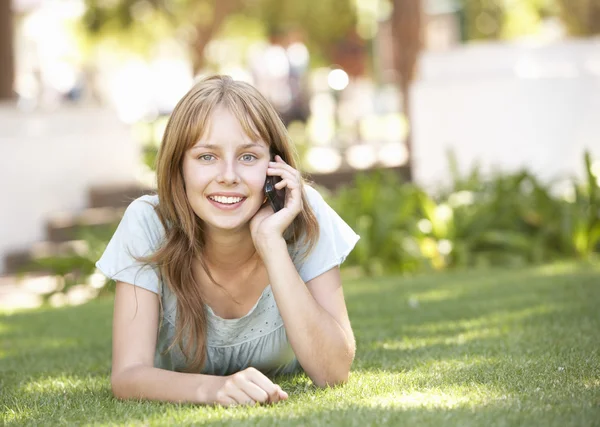 十几岁的女孩躺在使用移动电话的公园 — 图库照片