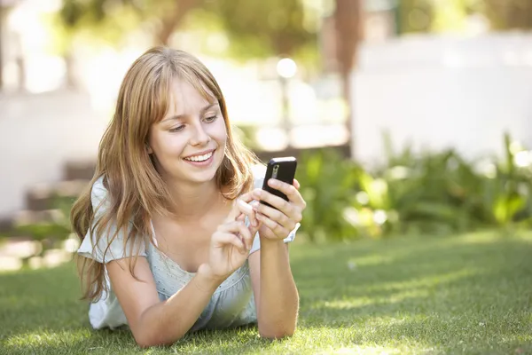 Adolescente acostada en el parque usando teléfono móvil — Foto de Stock