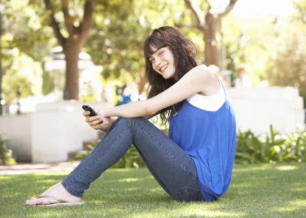 少女坐在公园使用移动电话的肖像 — 图库照片