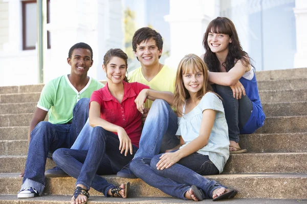 Grupo de amigos adolescentes sentados en la universidad pasos fuera — Foto de Stock