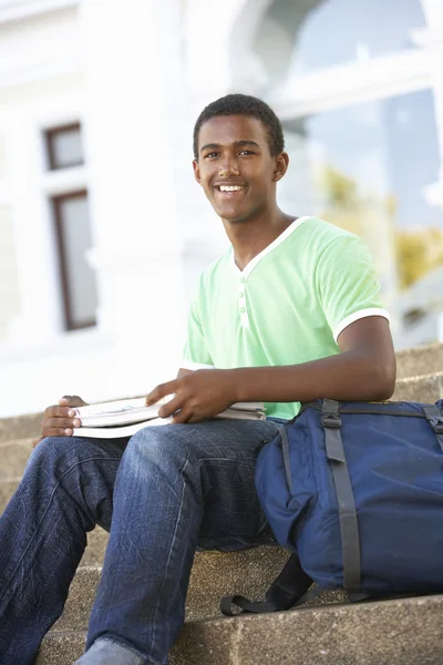 Hombre adolescente estudiante sentado fuera en la universidad pasos — Foto de Stock