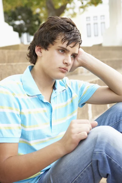 Infeliz masculino adolescente estudante sentado fora na faculdade passos — Fotografia de Stock