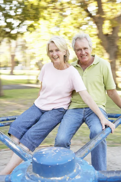 Äldre par ridning på rondellen i park — Stockfoto