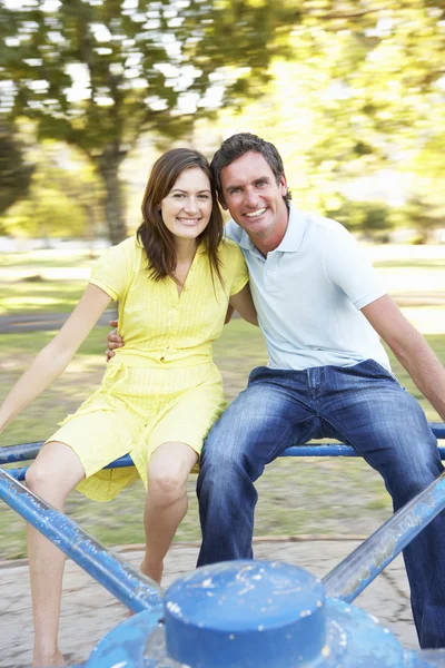 Молодая пара едет на карусели в парке — стоковое фото