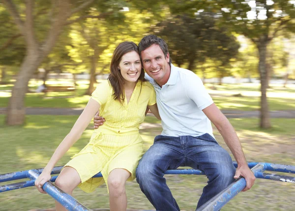 Молодая пара едет на карусели в парке — стоковое фото