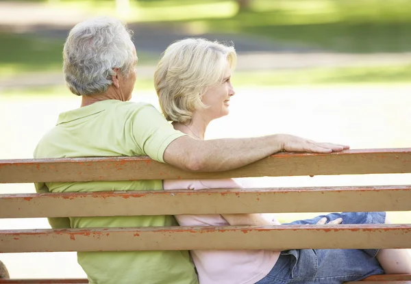 Старшая пара, сидящая вместе на скамейке в парке — стоковое фото