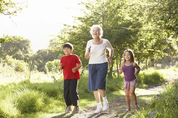 Büyükanne torunları ile parkta koşu — Stok fotoğraf